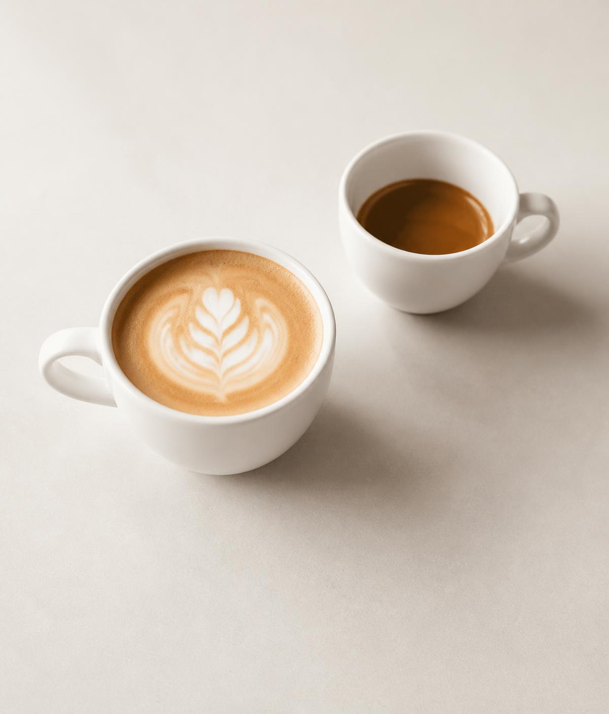 Flat white and espresso in plain white cups on a neutral surface